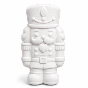Könnte beinhalten: Eine einfarbig weiße Nussknacker-Figur mit hohem Hut, markantem Schnurrbart und einer Uniform mit Schulterklappen und Gürtel. Das Objekt hat eine glatte, matte Oberfläche und ist in einer detaillierten, symmetrischen Soldatenform gegossen.