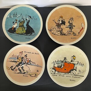May include: Four round ceramic plates featuring Norman Rockwell illustrations. The top left plate is blue with the text When in Rome. The top right is tan with Promenade à Paris. The bottom left is peach with Die walk am Rhein. The bottom right is light green with walking through merrie Englande.