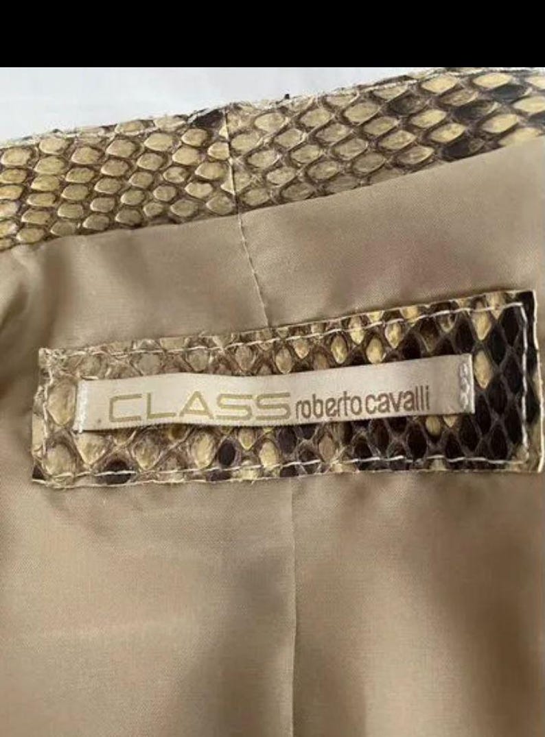 May include: A garment featuring a snakeskin pattern in shades of brown, tan, and black. A rectangular fabric label is stitched onto the interior, displaying the text CLASS roberto cavalli in black lettering against a light beige background.