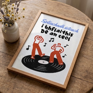 May include: A framed print featuring two figures in white shirts and orange trousers dancing on a black vinyl record. The text reads Spléachadh isteach i bhflaithis Dé an ceol in blue and black ink. Musical notes float around the figures.