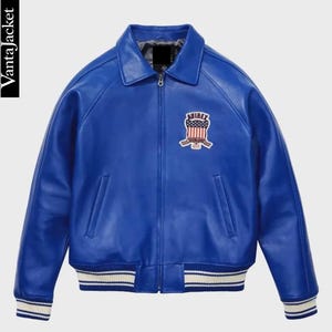 May include: A vibrant blue leather jacket with a classic collar and a zip-up front. Features a patch on the chest with a red, white, and blue design. The cuffs and hem have white stripes. The text "Vanta Jacket" is on the left side.