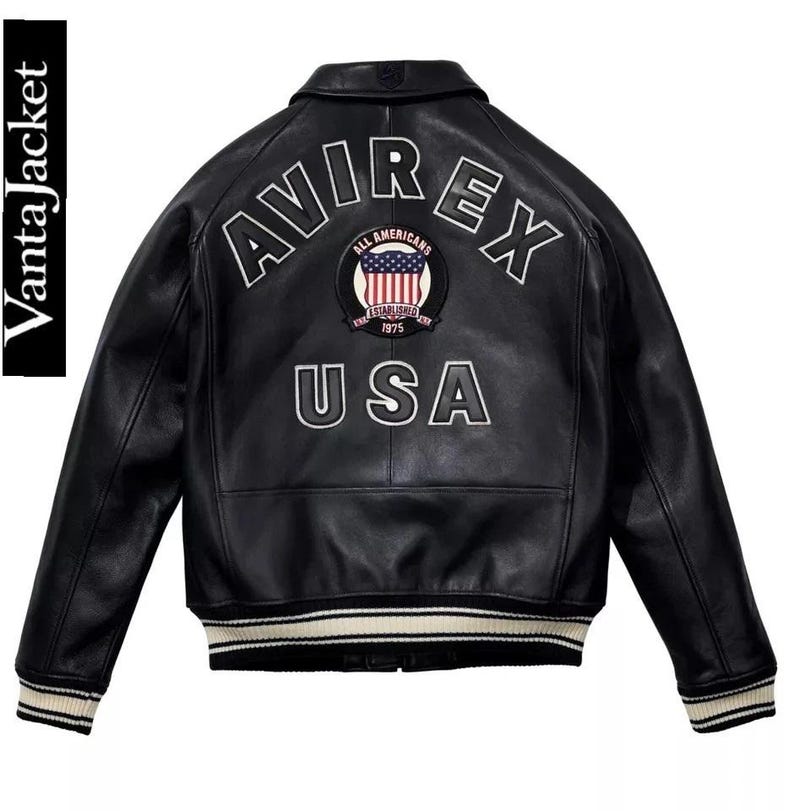 May include: Black leather jacket with white embroidered "AVIREX USA" lettering and a circular patch featuring the American flag. The jacket has a ribbed collar, cuffs, and hem with white and black stripes. The brand name "VantaJacket" is printed vertically on the left side.