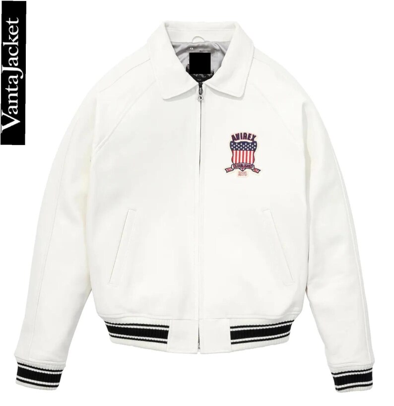 May include: White bomber jacket with a collar, zipper closure, and black and white striped cuffs and hem. Features an embroidered emblem with the text "AVIREX" and an American flag design. The jacket has the text "VantaJacket" on the left side.