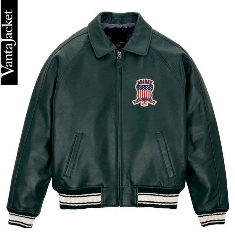 May include: A dark green leather jacket with a zip-up front, collar, and ribbed cuffs and hem. The jacket features a patch with a red, white, and blue design on the chest. The brand name "Vanta Jacket" is visible on the left side.