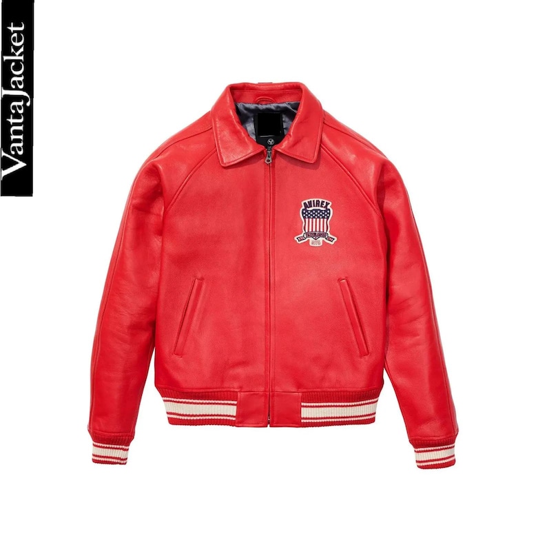 May include: A vibrant red leather jacket with a classic bomber style. Features a collared neckline, a zipper closure, and a patch on the chest with the word "AIRIRE" and a patriotic design. The cuffs and hem have white and red striped detailing.