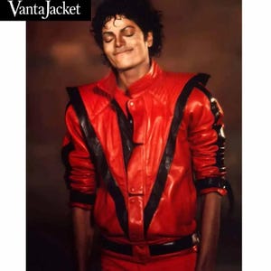 Può includere: Giacca in pelle rossa con dettagli neri, colletto alto e silhouette aderente. La giacca ha una chiusura con bottoni e una cintura nera. Il marchio "VantaJacket" è visibile in alto a sinistra.