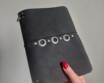 Cuaderno tríptico A5 de cuero negro con detalles metálicos, hecho a mano.
