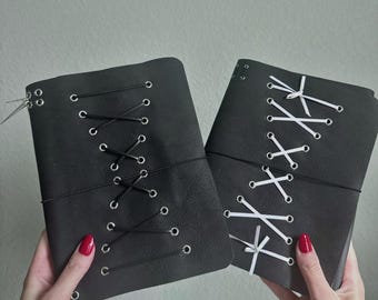 Cuaderno tríptico A5 de cuero negro con detalle de cordones, hecho a mano.