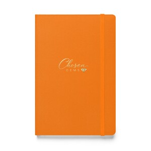 May include: An orange notebook with the gold text "Chosen Gems" and a diamond symbol. The notebook has an elastic band closure. The cover is a solid orange color.