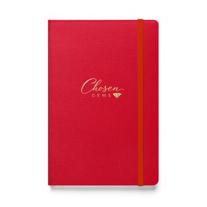 May include: A red notebook with the gold text "Chosen Gems" and a diamond graphic. The notebook has an orange elastic band closure. The cover has a textured appearance.