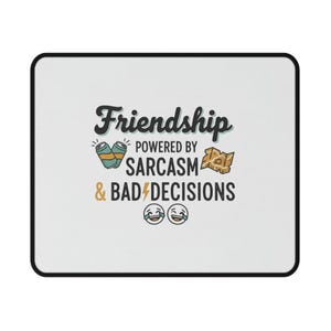 以下が含まれることがあります： 黒い縁取りのある白い長方形のマウスパッド。マウスパッドには、遊び心のあるフォントで「Friendship powered by Sarcasm & Bad Decisions」というテキストが記載されています。デザインには、ビール缶、プレッツェル、笑っている絵文字の漫画画像が含まれています。