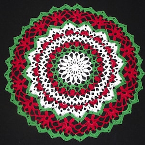 May include: A white, green, and red crocheted doily with a floral design.
