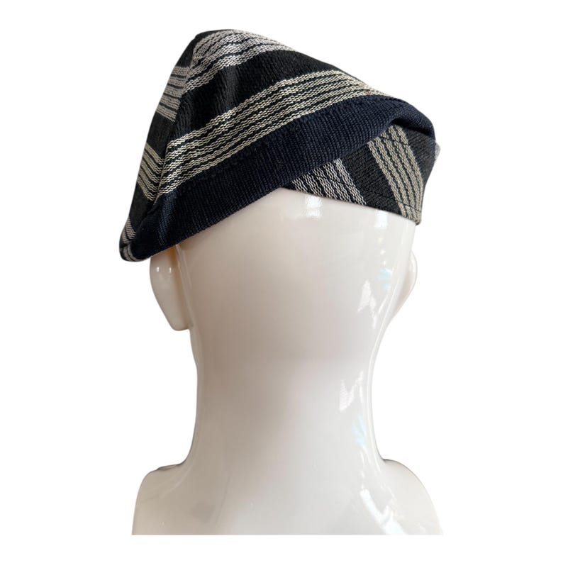 May include: A black and grey striped beret. The hat is made of a woven fabric with alternating black and grey stripes. The hat is displayed on a white mannequin head.