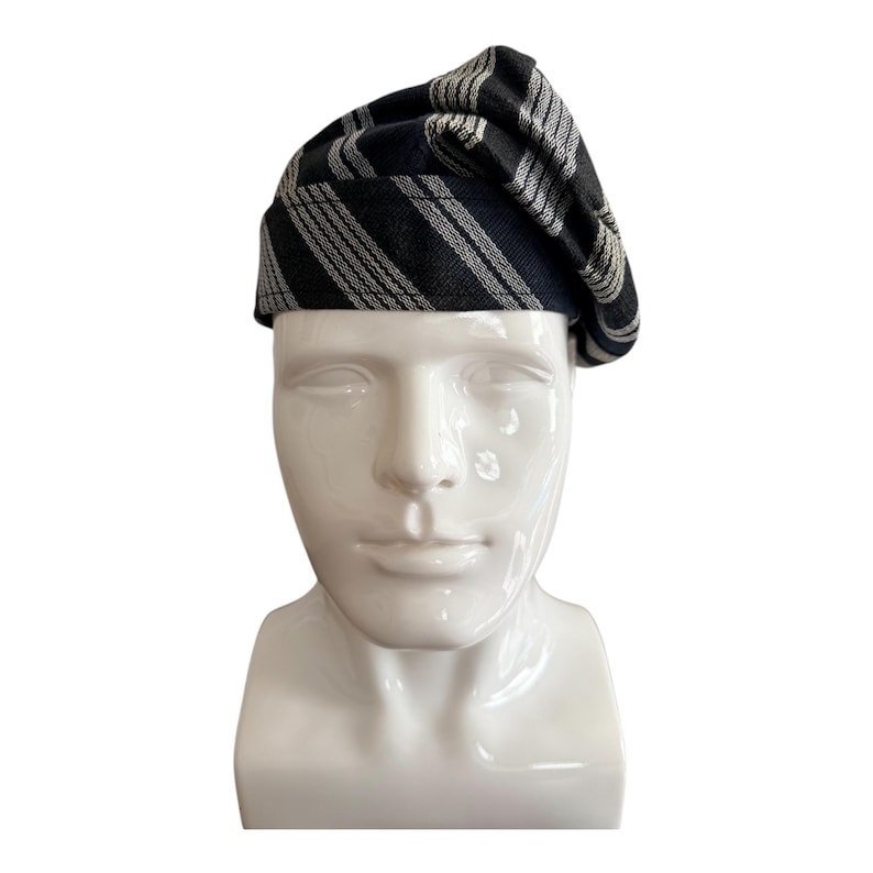 May include: A black and white striped beret hat. The hat is displayed on a white mannequin head. The beret features a classic design with alternating black and white stripes, offering a stylish accessory.