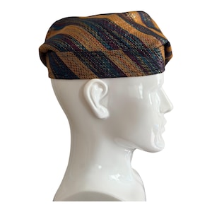 May include: A patterned hat with gold, brown, blue, and purple stripes. The hat is displayed on a white mannequin head, showcasing its design and shape. The hat's fabric has a subtle sheen, adding to its visual appeal.