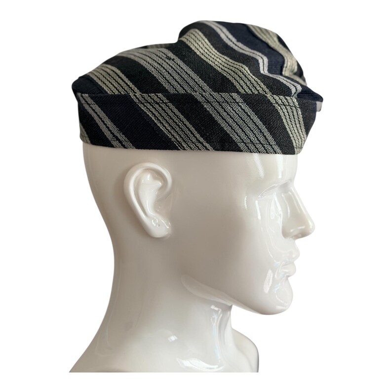 May include: A black and white striped hat with a rounded top, worn on a white mannequin head. The hat features diagonal stripes in black and off-white. The hat's brim is a solid black colour.