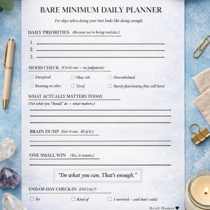 Puede incluir: Un planificador diario blanco titulado "Bare Minimum Daily Planner" con secciones para prioridades, control del estado de ánimo y una lluvia de ideas. El planificador incluye el texto "Haz lo que puedas. Eso es suficiente" y está rodeado de un bolígrafo, cristales y una taza de café.