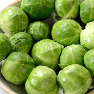Peut inclure: Une collection de choux de Bruxelles frais et crus aux feuilles vert vif étroitement serrées. Ces petits légumes ronds sont regroupés, affichant des textures fermes et lisses avec des nuances variées de feuillage vert clair à foncé.