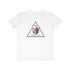May include: White t-shirt with a graphic of a cartoon eggplant holding a peanut. The eggplant is purple with a green stem and is inside a black triangle with the text "WARNING: CONTAINS NUTS."