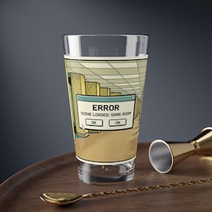 May include: A clear glass tumbler featuring a graphic print of a computer error message box that reads ERROR SCENE LOADED: SAME ROOM with two OK buttons, set against a background illustration of a yellow-toned, empty office hallway.