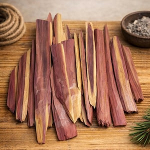 Puede incluir: Una colección de piezas de madera de cedro rojo y amarillo dispuestas sobre una superficie de madera. Las piezas de madera tienen un aspecto natural y texturizado. También se ve un cuenco pequeño con contenido gris y una bobina de cuerda.