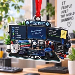 May include: A decorative acrylic ornament featuring a detailed IT support desk setup with three computer monitors, a keyboard, a mouse, a mug labeled 'TRUST ME I'M IT SUPPORT', a small character figure, and the name 'ALEX' printed on the desk mat.