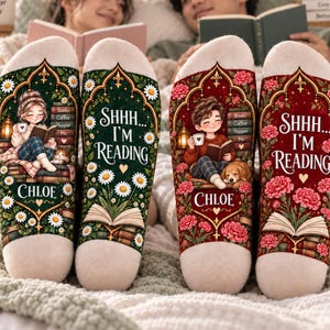 May include: Two pairs of cream-colored socks featuring illustrations of people reading books. One pair has a green background with daisies and a girl named Chloe, the other has a red background with carnations and a boy named Chloe. Both say SHHH... I'M READING.
