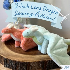 May include: Two plush dragon toys, one coral and one mint green, featuring soft fabric, small horns, and wings. A light blue banner at the top displays the text 12-Inch Long Dragon Sewing Pattern! and a needle graphic. A PDF Download label is at the bottom.