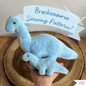 May include: A light blue plush Brachiosaurus dinosaur toy with a smaller version held in a hand. The text "Brachiosaurus Sewing Pattern!" is on a banner above the dinosaurs. A PDF download is also available.