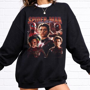 May include: Black sweatshirt featuring a graphic of Spider-Man with the text "Spider-Man Peter Parker" in red and orange. The design includes multiple images of the character in his suit. The sweatshirt has a crew neck and long sleeves.