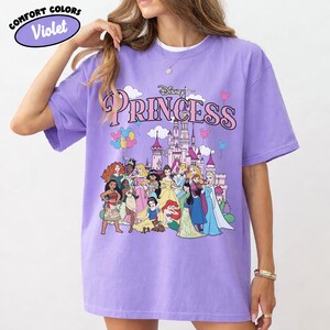 May include: A white ceramic mug with a black handle and the text "But First, Coffee" in a bold, black font. The mug is set against a blurred background, suggesting a cozy setting.