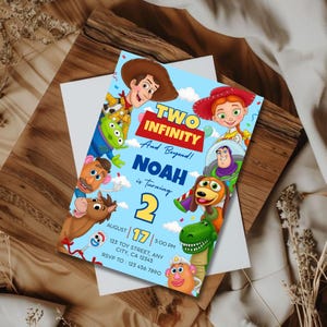 May include: A light blue birthday invitation card featuring cartoon characters including a cowboy, cowgirl, space ranger, green dinosaur, and potato figures. The text reads: TWO INFINITY And Beyond! NOAH is turning 2 AUGUST 17 5:00 PM.