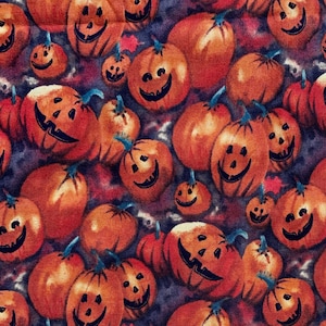 May include: A seamless fabric pattern featuring orange and brown jack-o'-lantern faces on a dark purple background. The jack-o'-lanterns are arranged in a random pattern and are all smiling.