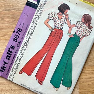 以下が含まれることがあります： レトロなデザインのヴィンテージMcCall's 3678ソーイングパターン。パターンには、赤いフレアパンツと緑色のフレアパンツのイラストが描かれており、花のラップトップと組み合わせています。パッケージは紫と白で、サイズと価格の情報が記載されています。