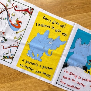 May include: A fabric panel featuring illustrations and quotes from a children's book. The panel includes a blue elephant on a yellow background with the text "Don't give up! I believe in you all!" and "A person's a person, no matter how small!"