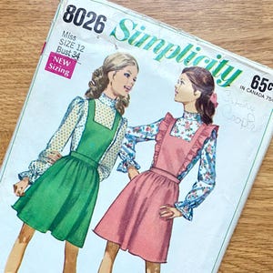 May include: Vintage Simplicity sewing pattern, size 12, featuring illustrations of two young girls wearing dresses. The pattern cover is light green and white with the number 8026 at the top. The text "Simplicity" is in a script font. The price is 65¢.