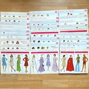 May include: A set of 10 vintage sewing pattern cards featuring illustrations of women's clothing designs. The cards are labelled with categories such as "Pantsuits", "Raglan Style Dresses", "Classic Coats", "Fitted Jackets", "Princess Tops", "Shorts and Pants for Men", "Tops and Ties for Men", "Capes and Kaftans", "Edges and Trims", and "Young Dresses & Tops".