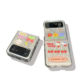 Peut inclure: Coque de t&eacute;l&eacute;phone transparente avec un design d&eacute;coratif. La coque pr&eacute;sente des fleurs de dessins anim&eacute;s, des cerises et le texte "Hello Lucky" et "Colorful Life". La coque est con&ccedil;ue pour un t&eacute;l&eacute;phone &agrave; clapet.