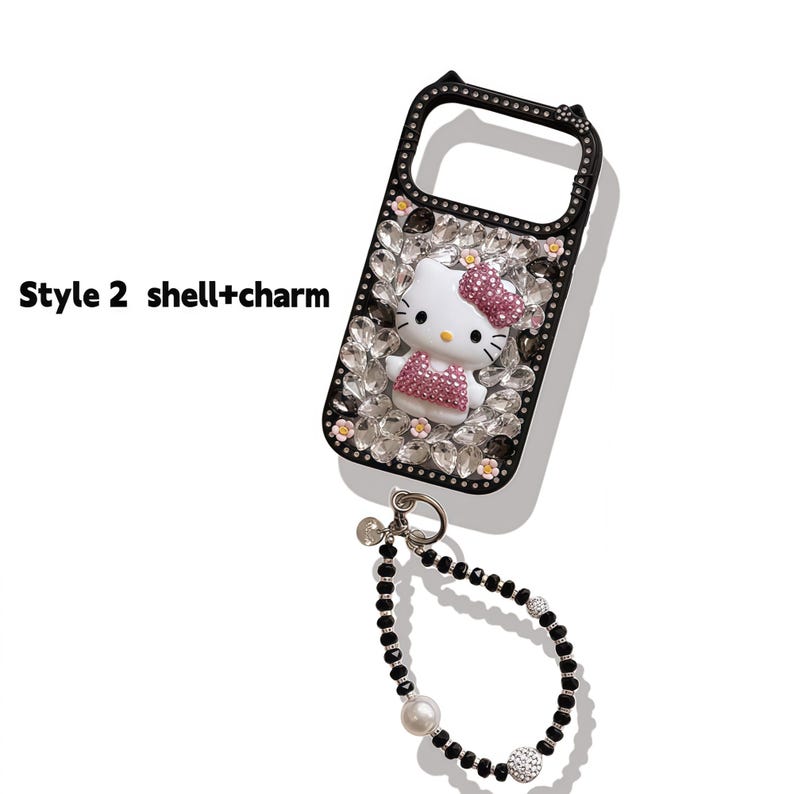 May include: Black phone case with a Hello Kitty design, embellished with rhinestones and a charm bracelet. The case features a white Hello Kitty figure with a pink bow and dress. The text "Style 2 shell+charm" is visible on the left side.