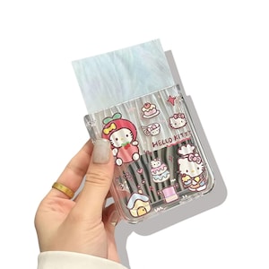 Peut inclure: Un porte-pinceaux en plastique transparent d&eacute;cor&eacute; de personnages Hello Kitty et d'illustrations de nourriture. Le support contient plusieurs pinceaux de maquillage et une mati&egrave;re duveteuse bleu clair. Les mots "Hello Kitty" sont imprim&eacute;s sur le c&ocirc;t&eacute;.