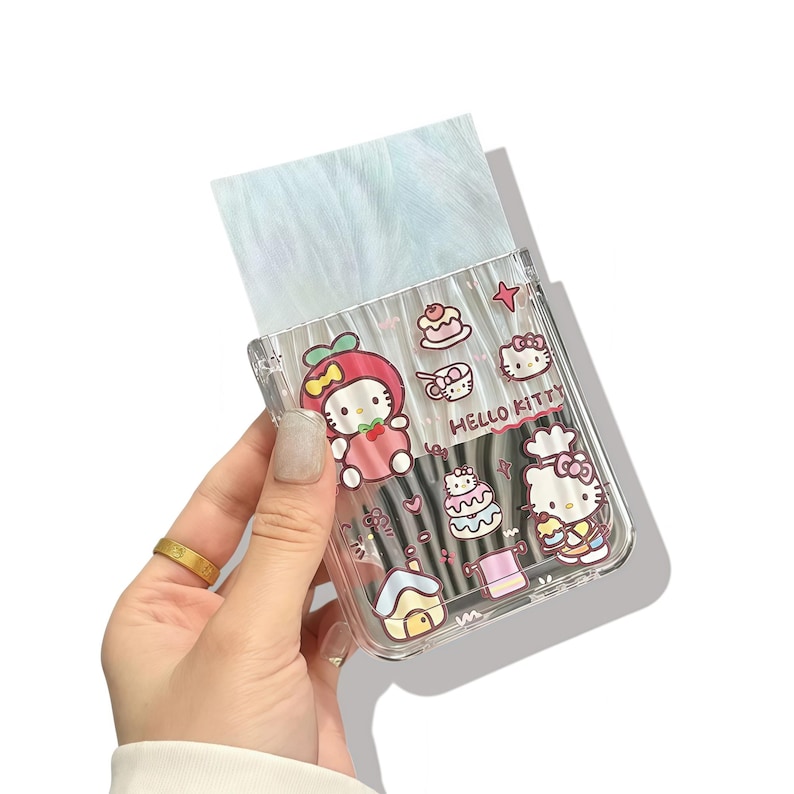 Peut inclure: Un porte-pinceaux en plastique transparent d&eacute;cor&eacute; de personnages Hello Kitty et d'illustrations de nourriture. Le support contient plusieurs pinceaux de maquillage et une mati&egrave;re duveteuse bleu clair. Les mots "Hello Kitty" sont imprim&eacute;s sur le c&ocirc;t&eacute;.