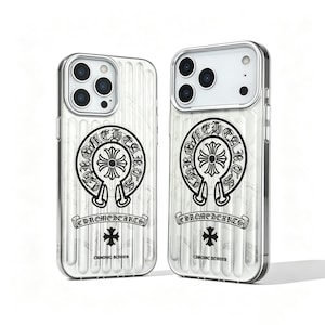 May include: Two silver and white phone cases. Each case features a black emblem with a cross design and the text "CHROMEHEARTS". The cases have a ribbed texture and a silver border.