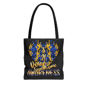 May include: Black tote bag with a black handle. The bag features a heart-shaped design made of blue and yellow handprints. The numbers "3 21" are in the center, with the words "Down Syndrome Awareness" below in gold and blue.