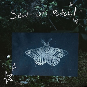 May include: A rectangular dark blue sew-on patch featuring a white, detailed moth illustration with intricate wing patterns and feathery antennae. The text "Sew-on Patch!" is written in white script at the top, accompanied by small white star doodles.