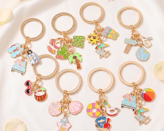 May include: A collection of seven gold-toned metal keychains, each featuring multiple colorful enamel charms with summer themes including flip-flops, palm trees, suns, beach chairs, seashells, surfboards, beach balls, and tropical drinks.
