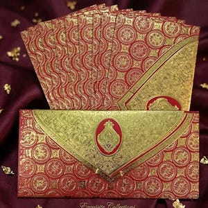 May include: A set of ornate red and gold invitation cards. The cards feature a repeating circular pattern with gold accents. The envelope has a gold flap with a red oval emblem. The text "Exquisite Collections" is at the bottom.