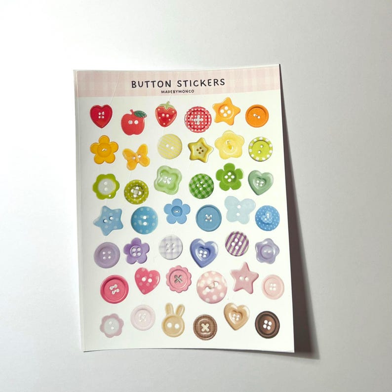 May include: A sheet of button stickers with various shapes and colors. The stickers include hearts, apples, strawberries, stars, flowers, and butterflies. The text "BUTTON STICKERS" is printed at the top of the sheet.