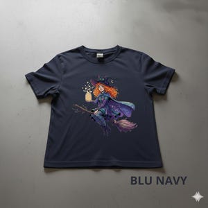 Könnte beinhalten: Marineblaues T-Shirt mit einer Illustration einer rothaarigen Hexe auf einem Besen. Die Hexe trägt ein lila Outfit und hält ein Glas mit leuchtenden Lichtern. Der Text "BLU NAVY" ist unten auf dem T-Shirt aufgedruckt.