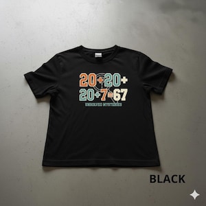 Può includere: T-shirt nera con la scritta "20+20+ 20+7=67" in arancione, verde acqua e bianco sporco. Il testo è sopra le parole "UNSOLVED MYSTERIES" in verde acqua. La parola "BLACK" è in basso.