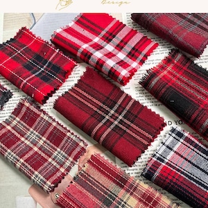May include: A collection of rectangular fabric swatches featuring various red, black, white, and tan plaid patterns. Each piece of textile has frayed, unfinished edges and displays a distinct tartan design with intersecting lines of different colors.